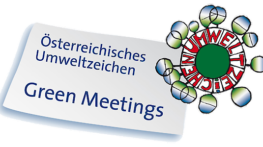 Ein Schild mit der Aufschrift Österreichisches Umweltzeichen Green Meetings neben einem kreisförmigen Logo mit dem Wort UMWELTZEICHEN in Rot und Grün, das auf umweltfreundliche Meetings hinweist.