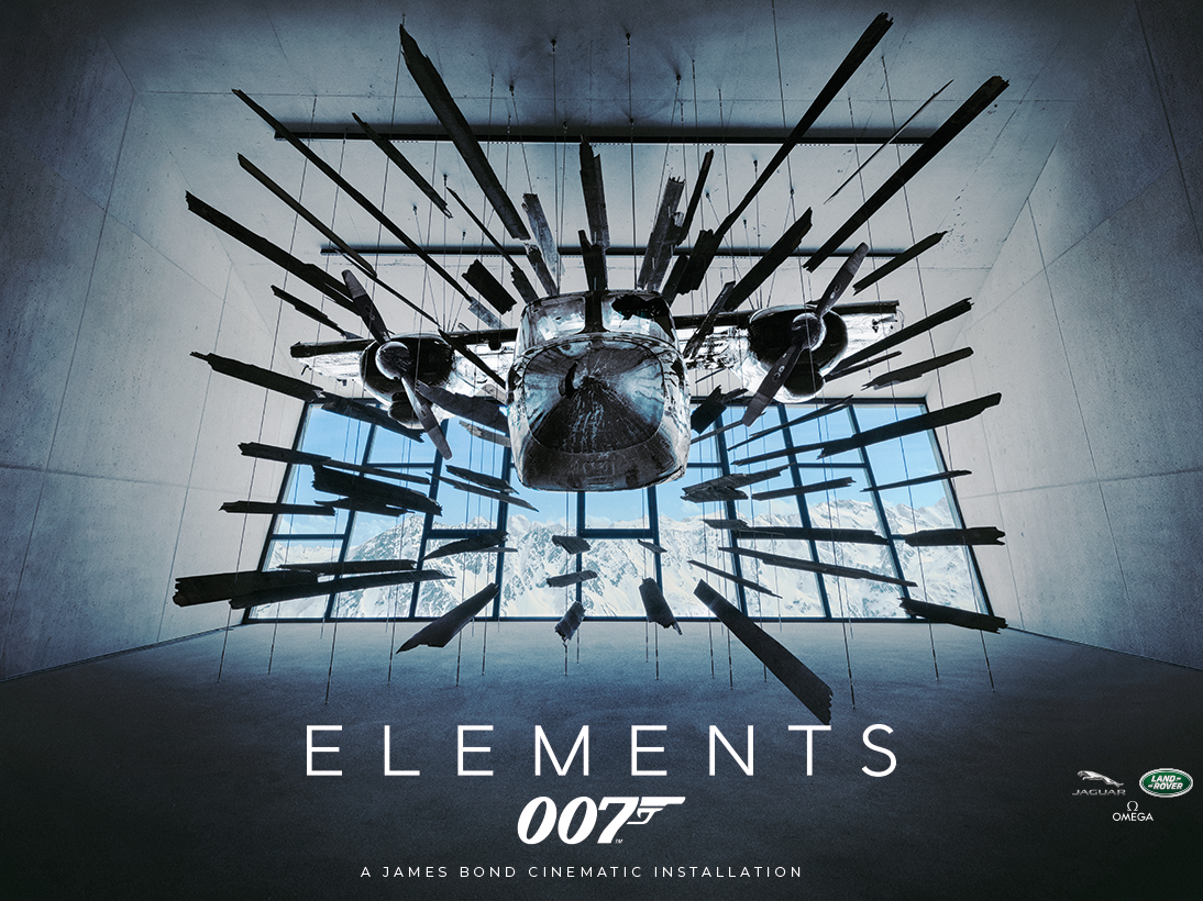 Airplane art installation in a modern room with glass windows, featuring the text Elements 007: A James Bond Cinematic Installation and logos of Jaguar, Land Rover, and Omega.